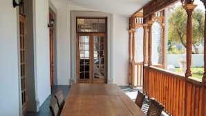 Una mesa de comedor de madera con sillas, una barandilla de madera y vistas al exterior.