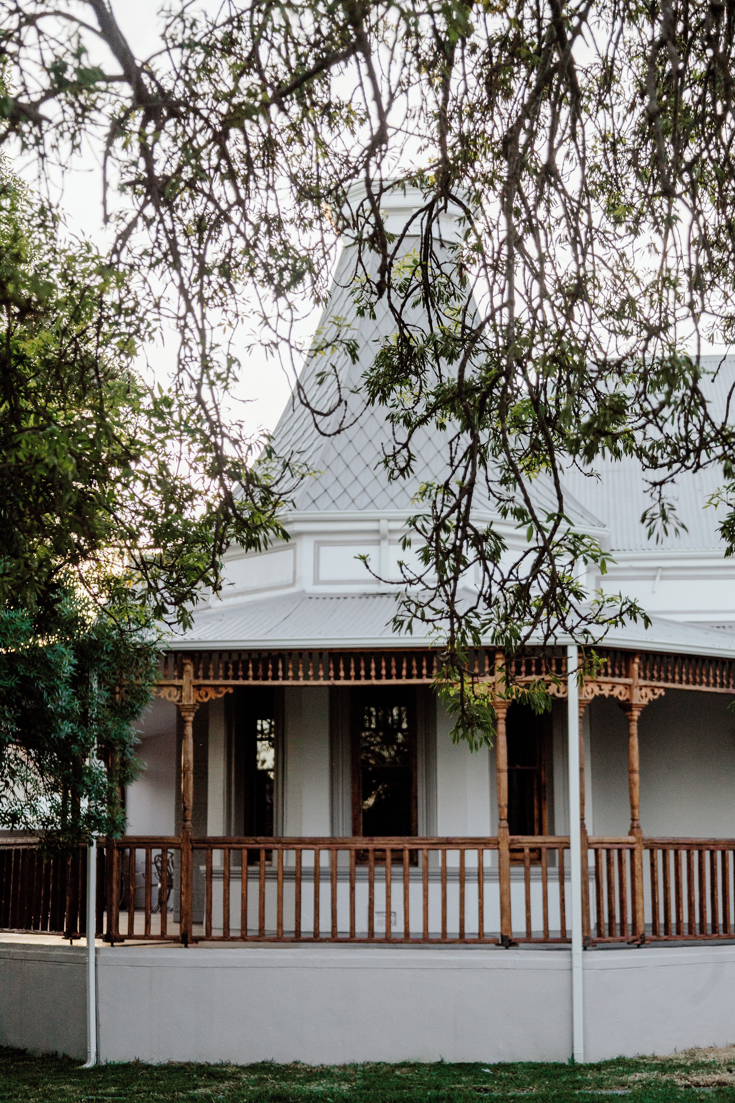 A white building with a covered porch and a fence.