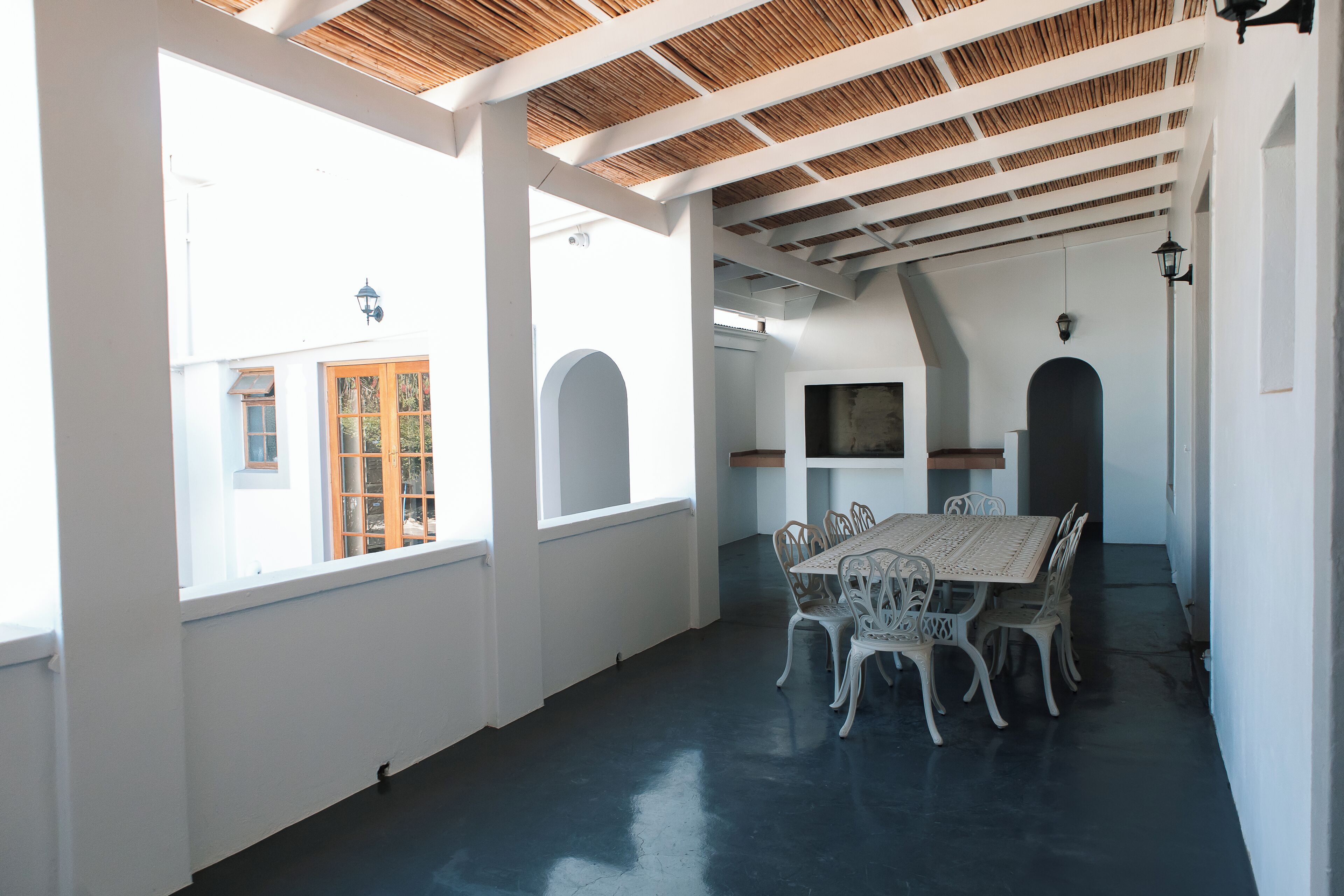 A spacious room with a large table and chairs, white walls, and a wooden ceiling.