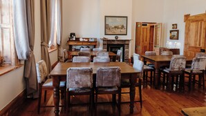 Comedor con mesas y sillas de madera, chimenea y candelabro.