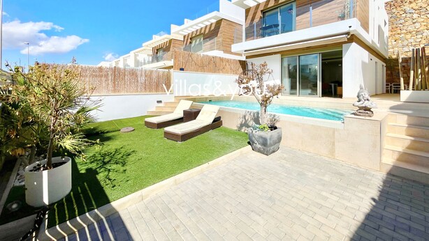 En modern villa med pool, utomhusmöbler och en välskött trädgård.