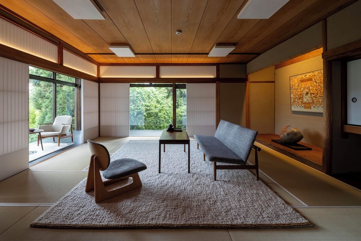 A traditional Japanese room with tatami flooring, a low table, a sofa, and a chair.