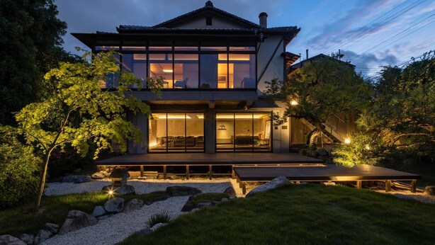 A modern two-story house with a large deck, surrounded by a well-maintained garden with rocks and trees. - Momoyama Onsen Tsukimikan (Kyoto)
