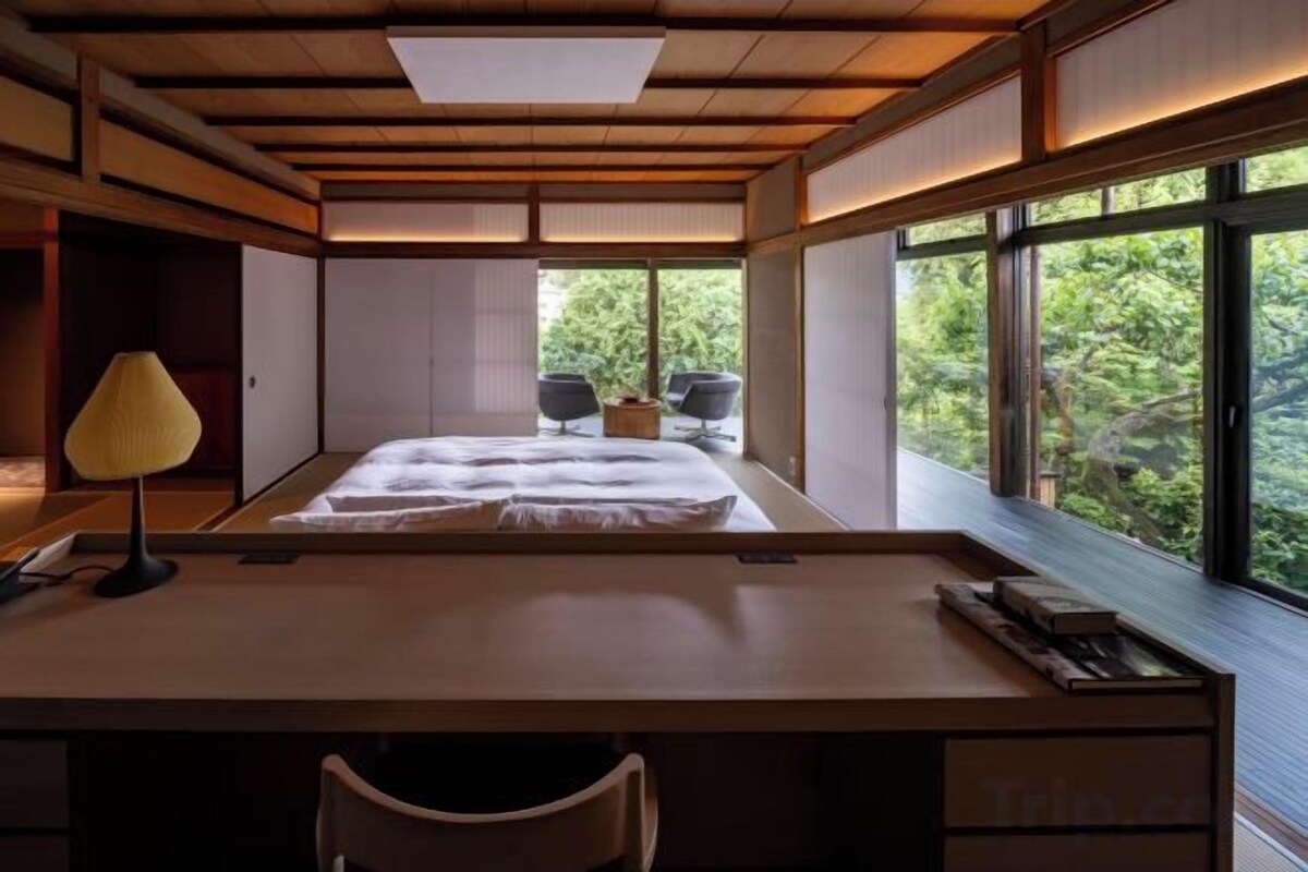 Una habitación con cama, escritorio y ventanas amplias.