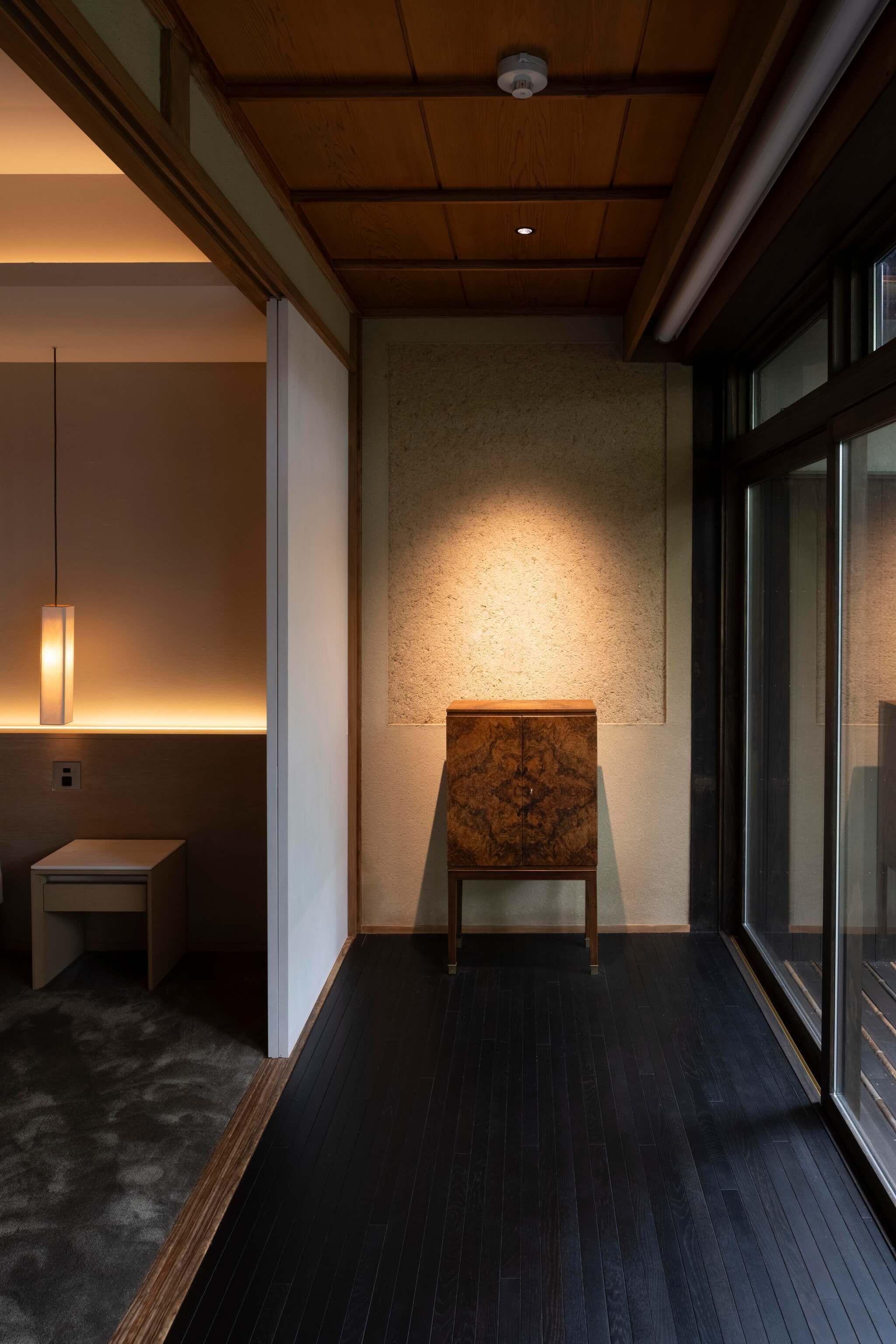 A modern interior with a wooden ceiling, a marble accent wall, and a dark wooden floor.