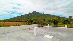 Terraza en la azotea con vistas a una montaña y vegetación circundante.