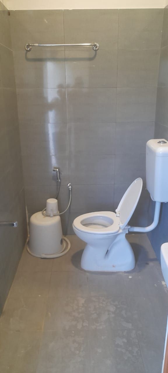 A small, enclosed bathroom with a toilet, a bidet, and a handrail.