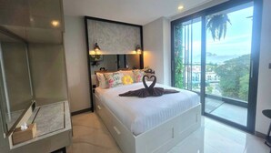 Un dormitorio moderno con una cama grande, televisión integrada y balcón con vistas a la ciudad.