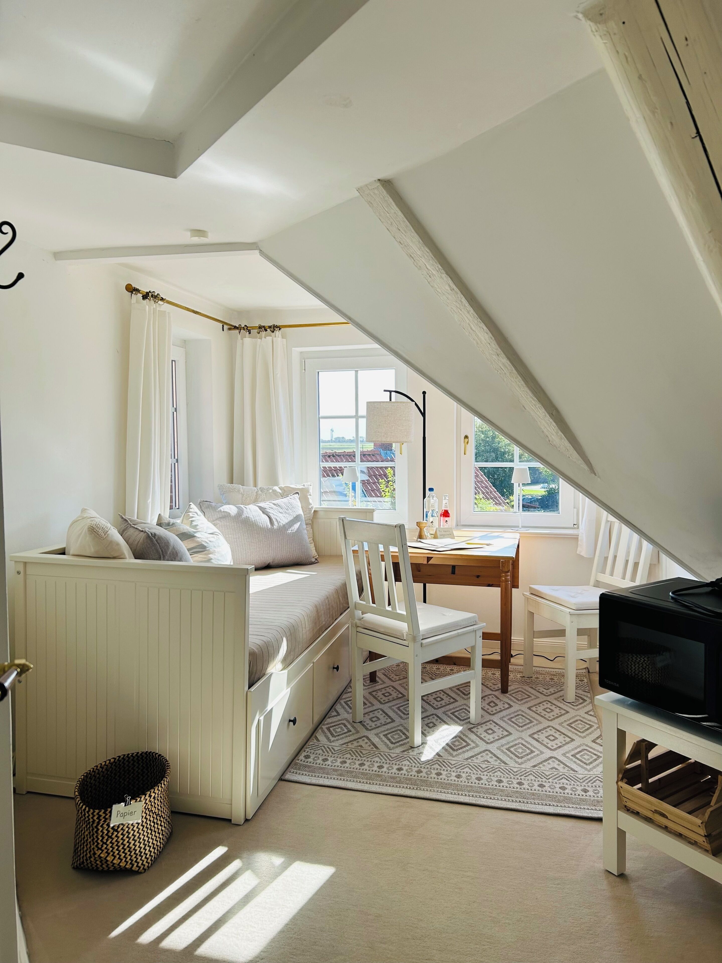 Une chambre confortable située sous les toits, avec un lit, un bureau et une télévision.