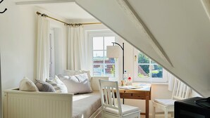 A cozy attic bedroom with a bed, a desk, and a TV. - Tower room in the Pilsumer Hof (Krummhörn)