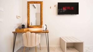 A modern room with a wooden desk, a chair, a mirror, a television displaying 'NETFLIX', and a small table. - Avenue Suites (Bologna)