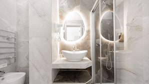 A modern bathroom with a white sink, a glass-enclosed shower, and marble walls. - Avenue Suites (Bologna)