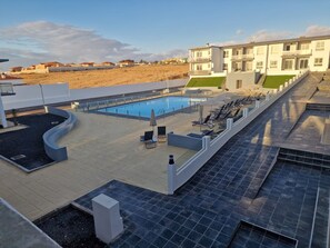 Une piscine sur le toit, avec des chaises longues, et un bâtiment moderne en arrière-plan.