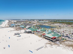 An aerial view of a coastal town with a beach, a marina, and several buildings with green roofs. - Coastal Haven: Heated Pools with a Beach Shuttle! (Destin)