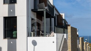 A modern building with a balcony, large windows, and a staircase leading to an upper level. - Casa Brisa by ACasaDasCasas (Carvoeira)