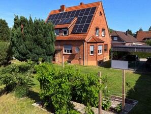 A house with a sloped roof, solar panels, and a garden with various plants.