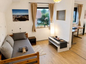 A modern bedroom with a bed, bedside table, lamp, and a view of the outdoors.