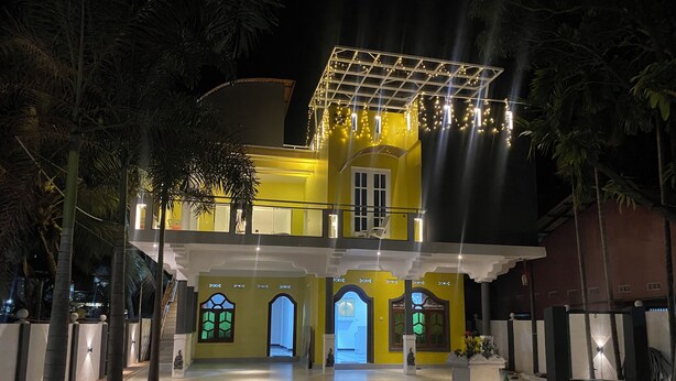 A two-story building with a yellow facade, multiple windows, and a covered entrance area.
