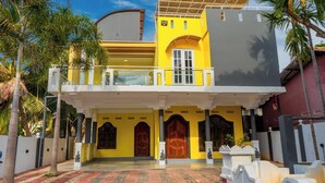 A two-story building with a balcony, large windows, and a tiled entrance.