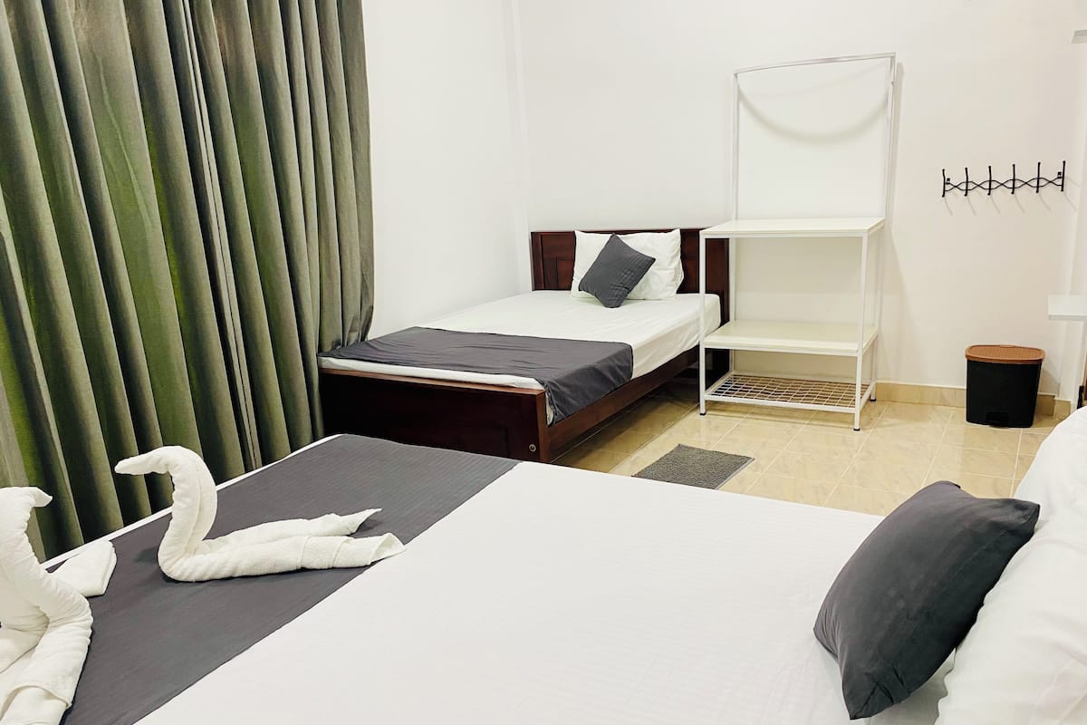 A hotel room with a bed, a chair, a small table, and a trash bin.