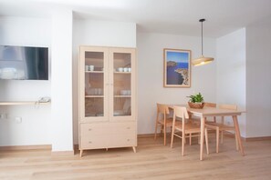 A dining area with a wooden table and chairs, a cabinet with glass doors, a hanging light fixture, and a framed picture on the wall.