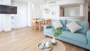 A modern living room with a sofa, a dining table, and a TV.