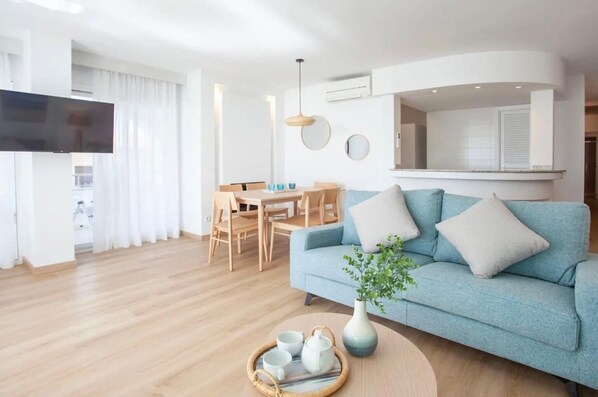 A modern living room with a sofa, a dining table, and a TV.
