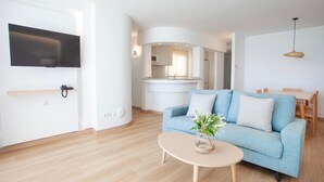 A modern living room with a sofa, coffee table, and a flat-screen TV mounted on the wall.