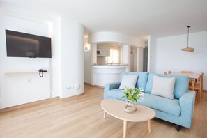 A modern living room with a sofa, coffee table, and a flat-screen TV mounted on the wall.