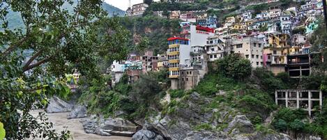 A hillside settlement with colorful buildings, a river in the foreground, and a rocky terrain.