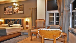 A hotel room with a bed, bedside tables, a chair, and a window with curtains. - Hotel US Tower (Devaprayāg)