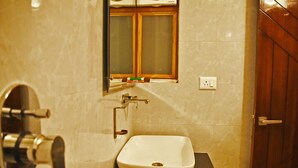 A bathroom with a white sink, a mirror, and a wooden door. - Hotel US Tower (Devaprayāg)