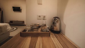 A wooden table with a tray holding kitchen items, a kettle, and a power outlet on the wall. - Hiraya Uluwatu (Pecatu)