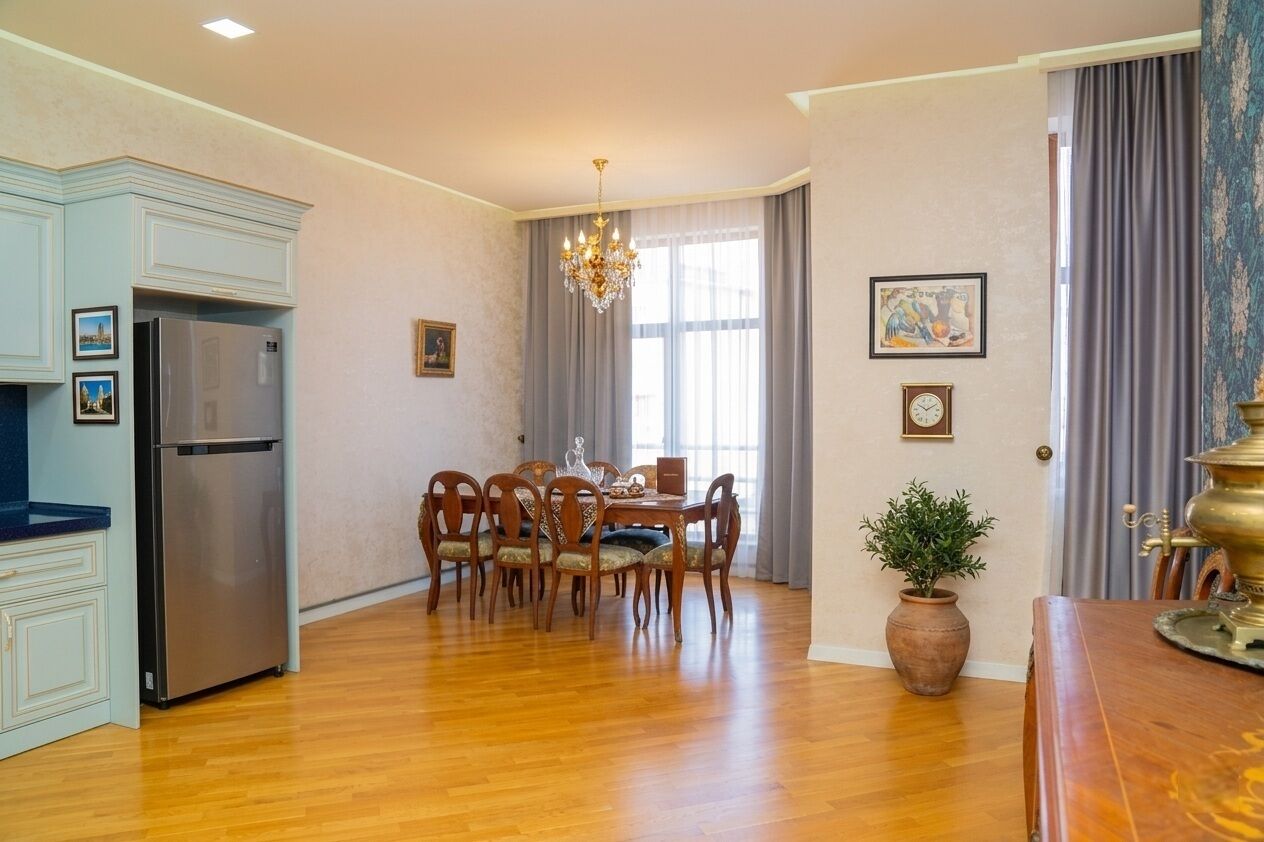 Zona pranzo con un lampadario, un tavolo in legno e sedie.