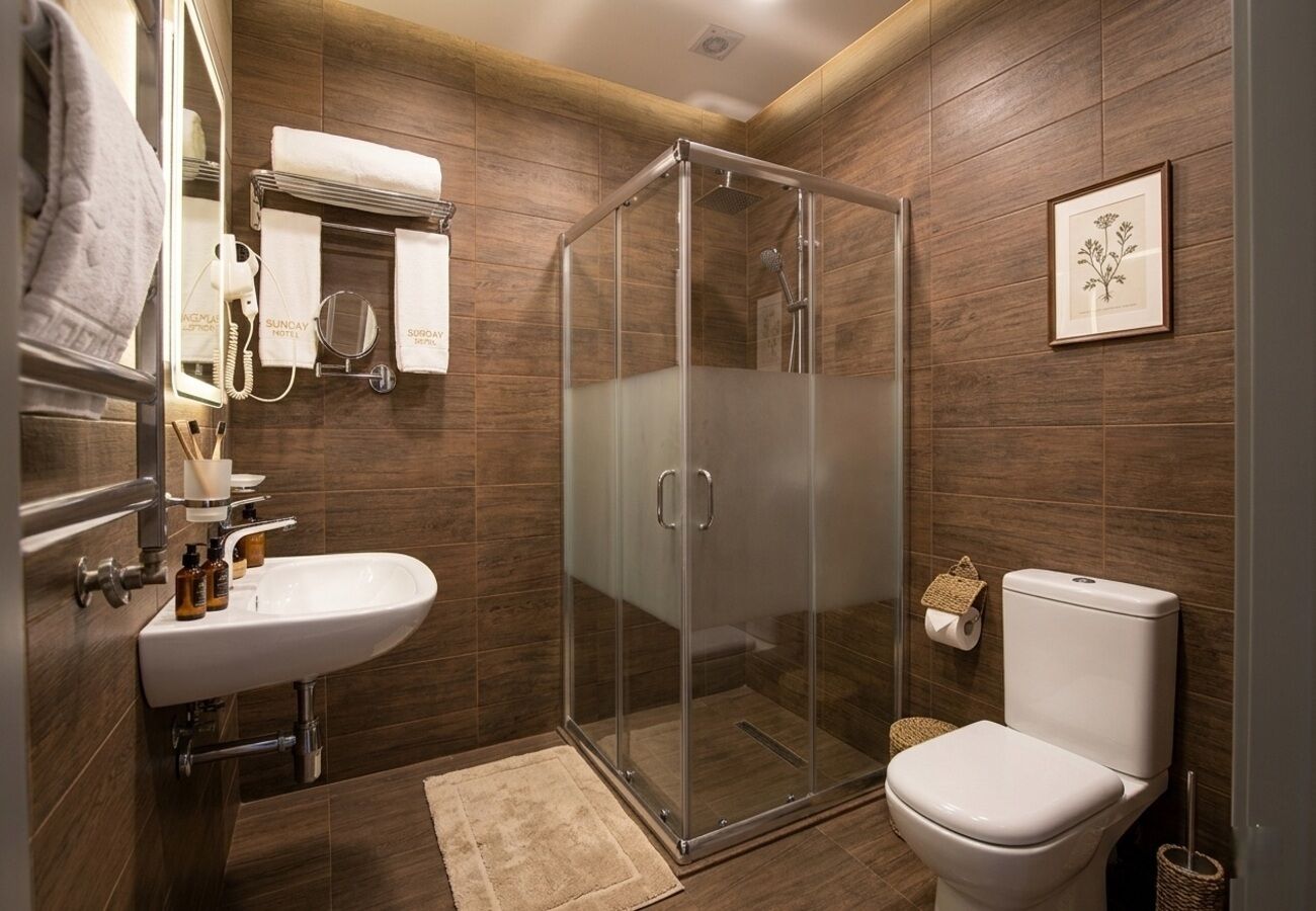 A modern bathroom with a glass shower enclosure, a white sink, and a toilet.