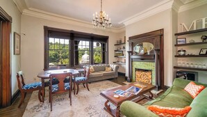 A living room with a fireplace, a dining area with a table and chairs, and a green sofa. - Marshall Inn Skyline Guestroom (Q/Q),Walk Downtown (Marshall)