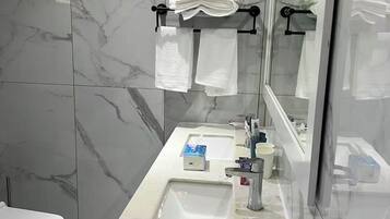Een moderne badkamer met een marmeren wastafel, een grote spiegel en een toilet.