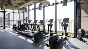 A gym with various exercise equipment, large windows, and a view of the outside. - Modern Studio Burj Khalifa View Upside Living (Dubai)