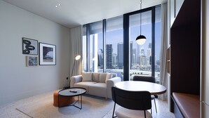 A modern hotel room with a large window offering a city view, a sofa, a round table, and a coffee table. - Modern Studio Burj Khalifa View Upside Living (Dubai)