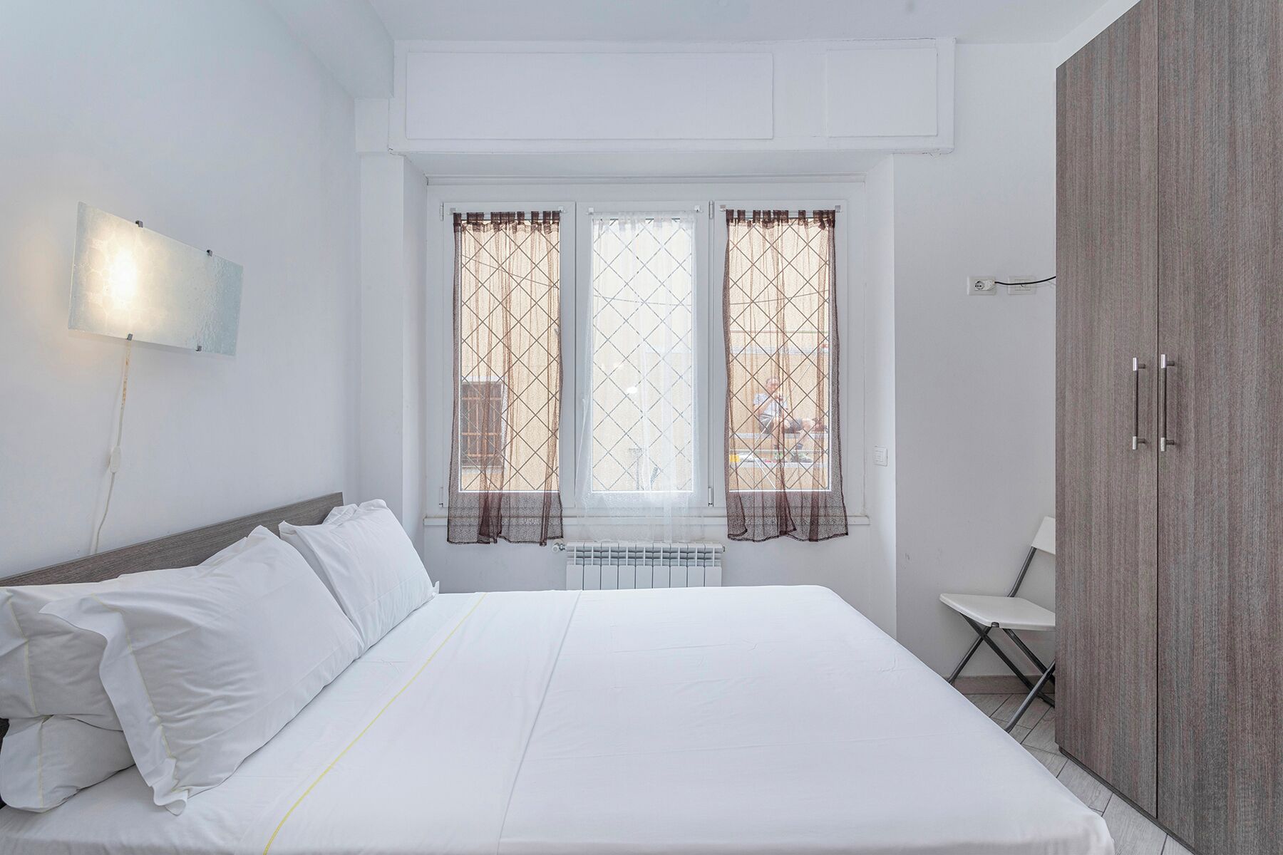 A bedroom with a bed, a nightstand, a chair, and a wardrobe.
