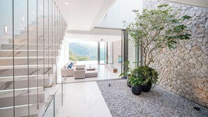 Ein modernes Interieur mit einer Glasstaircase, einer Sitzecke mit Aussicht und einer Steinwand mit Pflanzen.