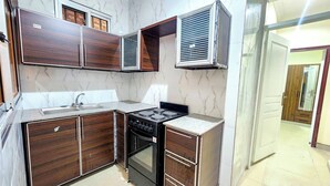 Une cuisine compacte avec des meubles de couleur bois foncé, une cuisinière encastrée et une hotte aspirante.