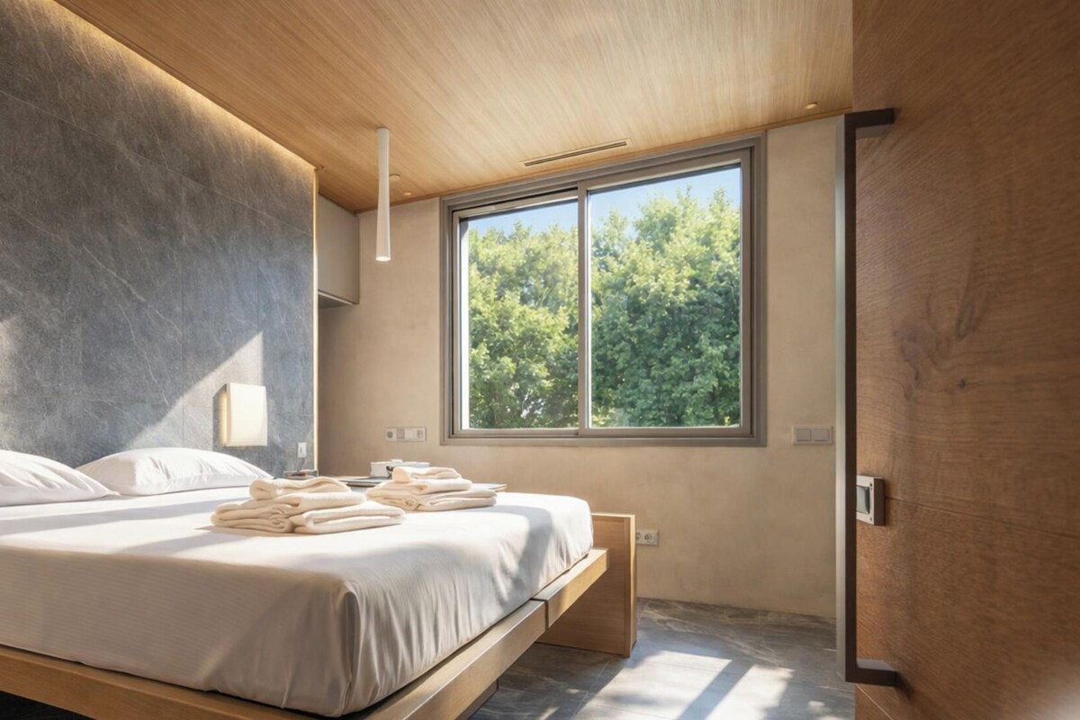 Ein modernes Schlafzimmer mit einem großen Bett, einem Fenster mit Blick auf Bäume und einer Holzzieldecke.