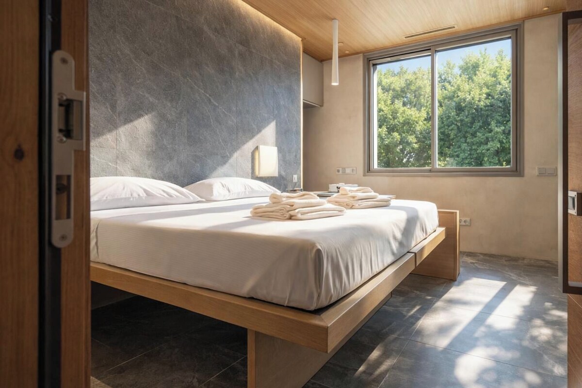 A modern bedroom with a bed, a window, and a view of trees.