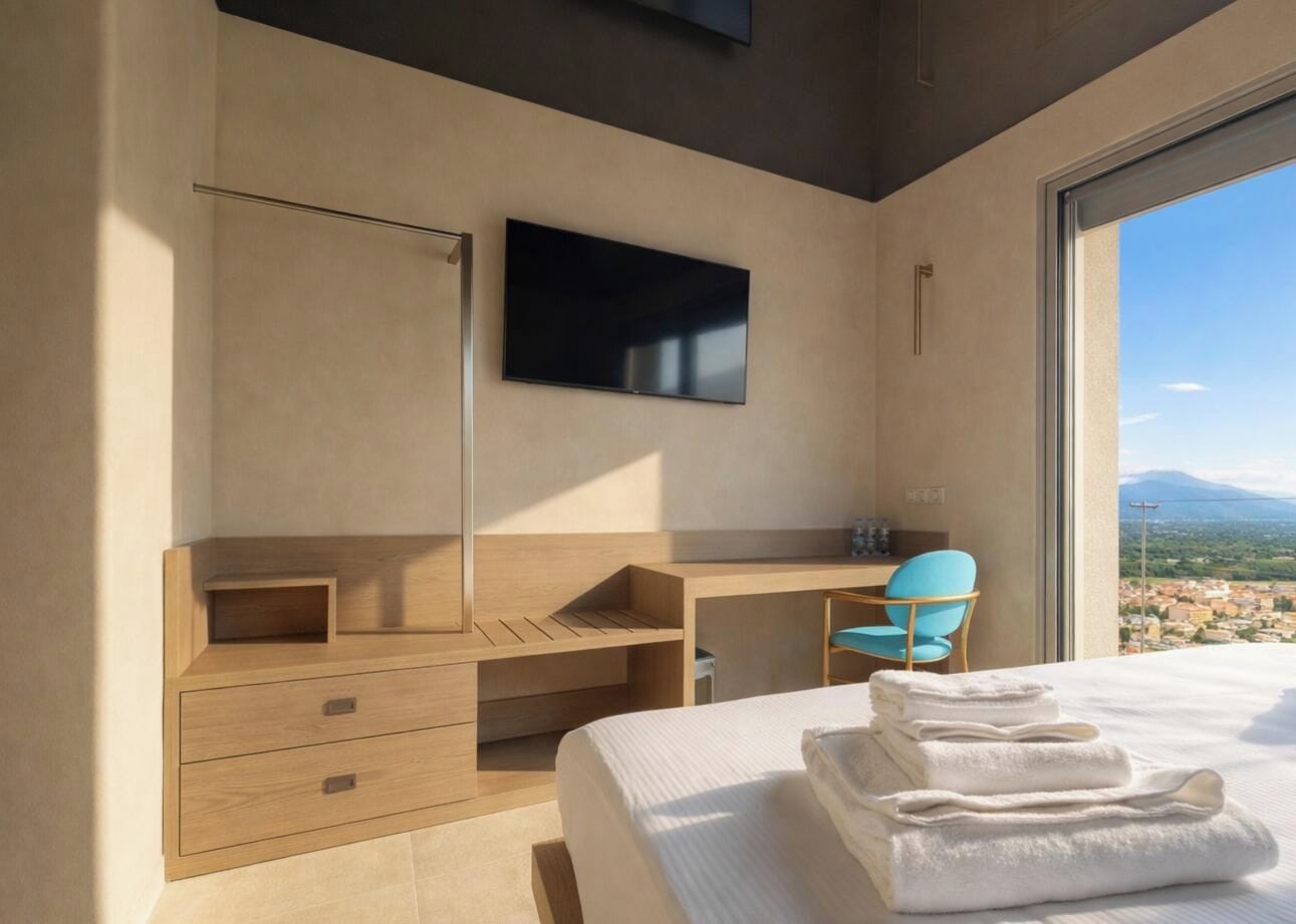 Quarto de hotel moderno com uma cama, uma escrivaninha, uma cadeira e uma televisão.