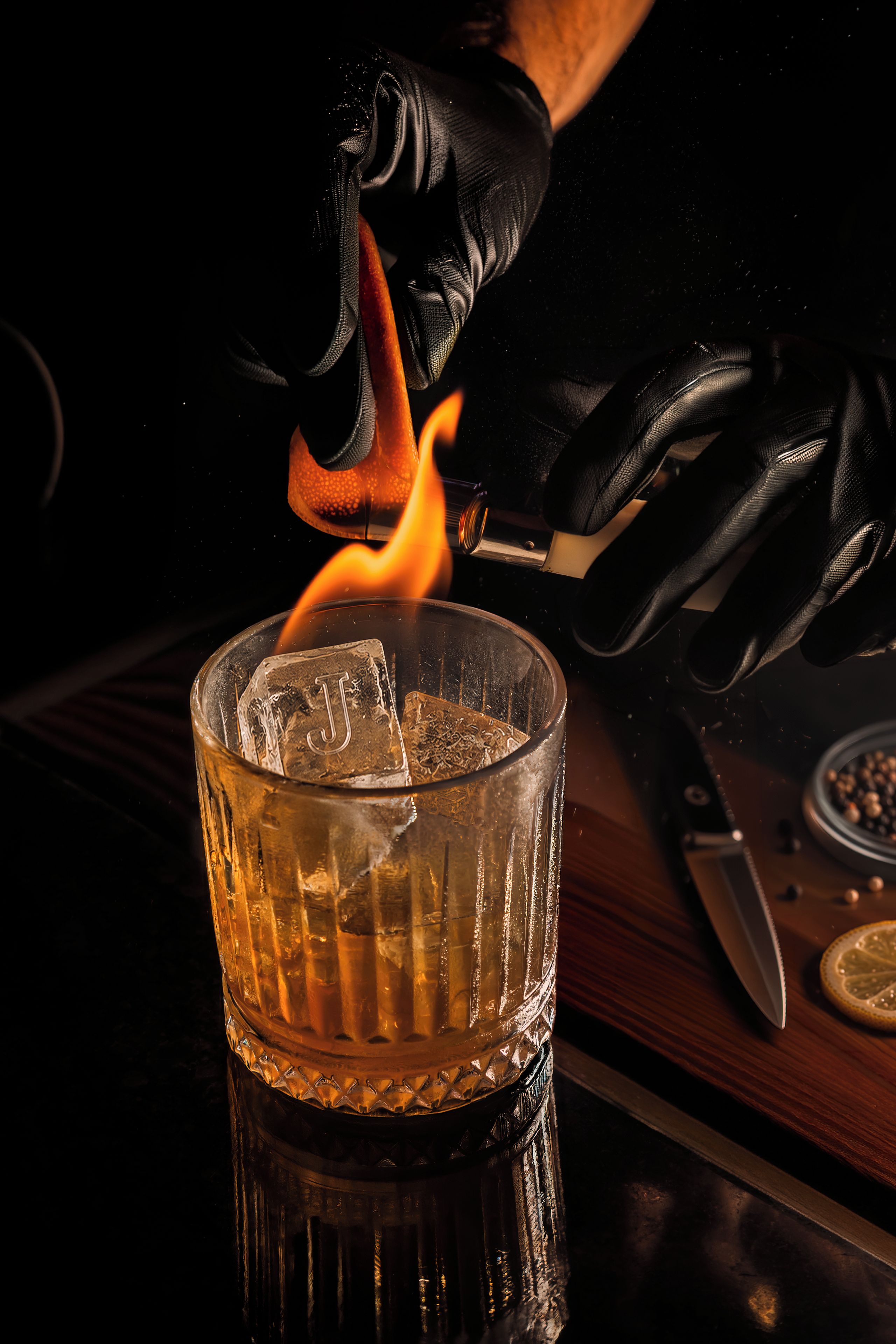 A hand lighting a match to ignite a flame above a glass container.