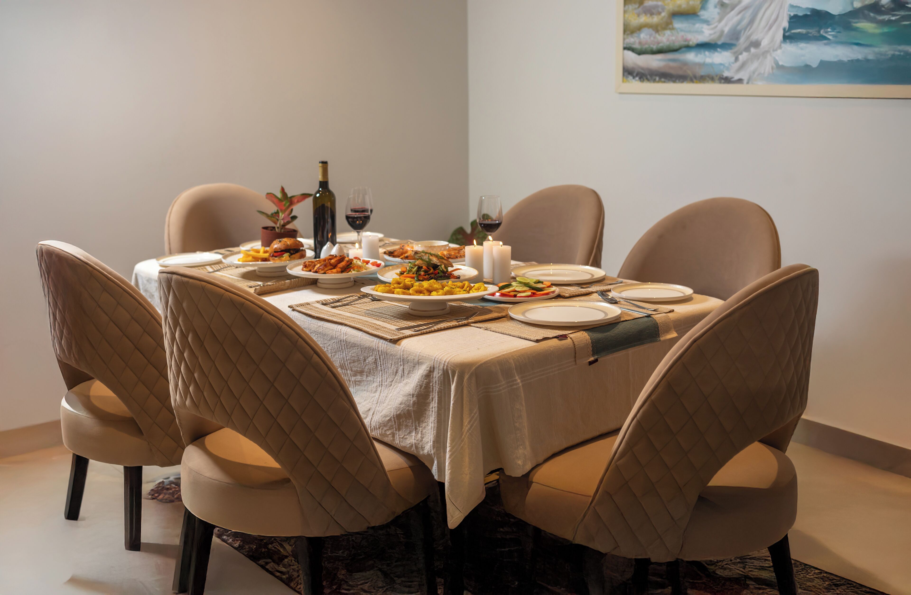 A dining table set with plates, glasses, and a bottle of wine, surrounded by cushioned chairs.