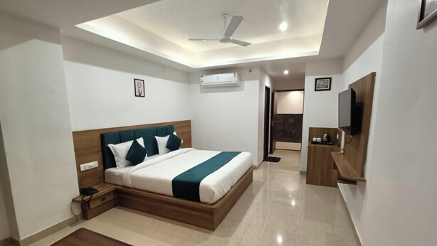 A modern hotel room with a bed, bedside table, and a small desk area. - Hotel Raas Inn (Udaipur)