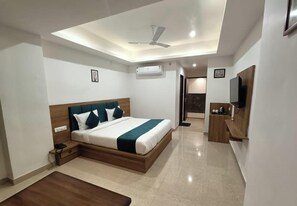 A modern hotel room with a bed, bedside table, and a small desk area. - Hotel Raas Inn (Udaipur)