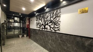 A hallway with a tree mural, a sign indicating room numbers 301 to 307, and a glass door entrance. - Hotel Raas Inn (Udaipur)
